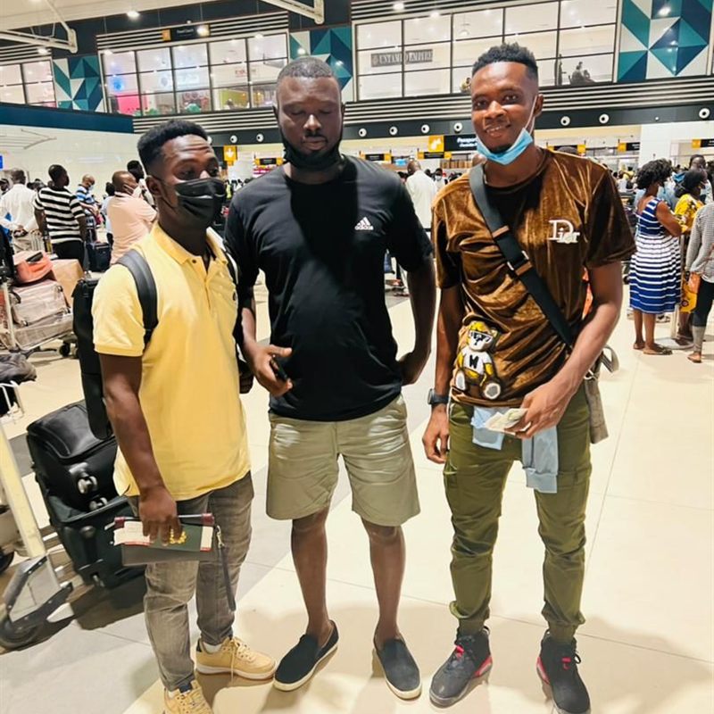 Three young men with travel documents in an airport departure hall
