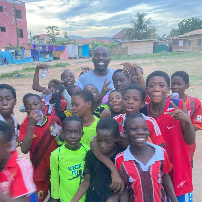 Children in football shirts crowding together and smiling at the camera